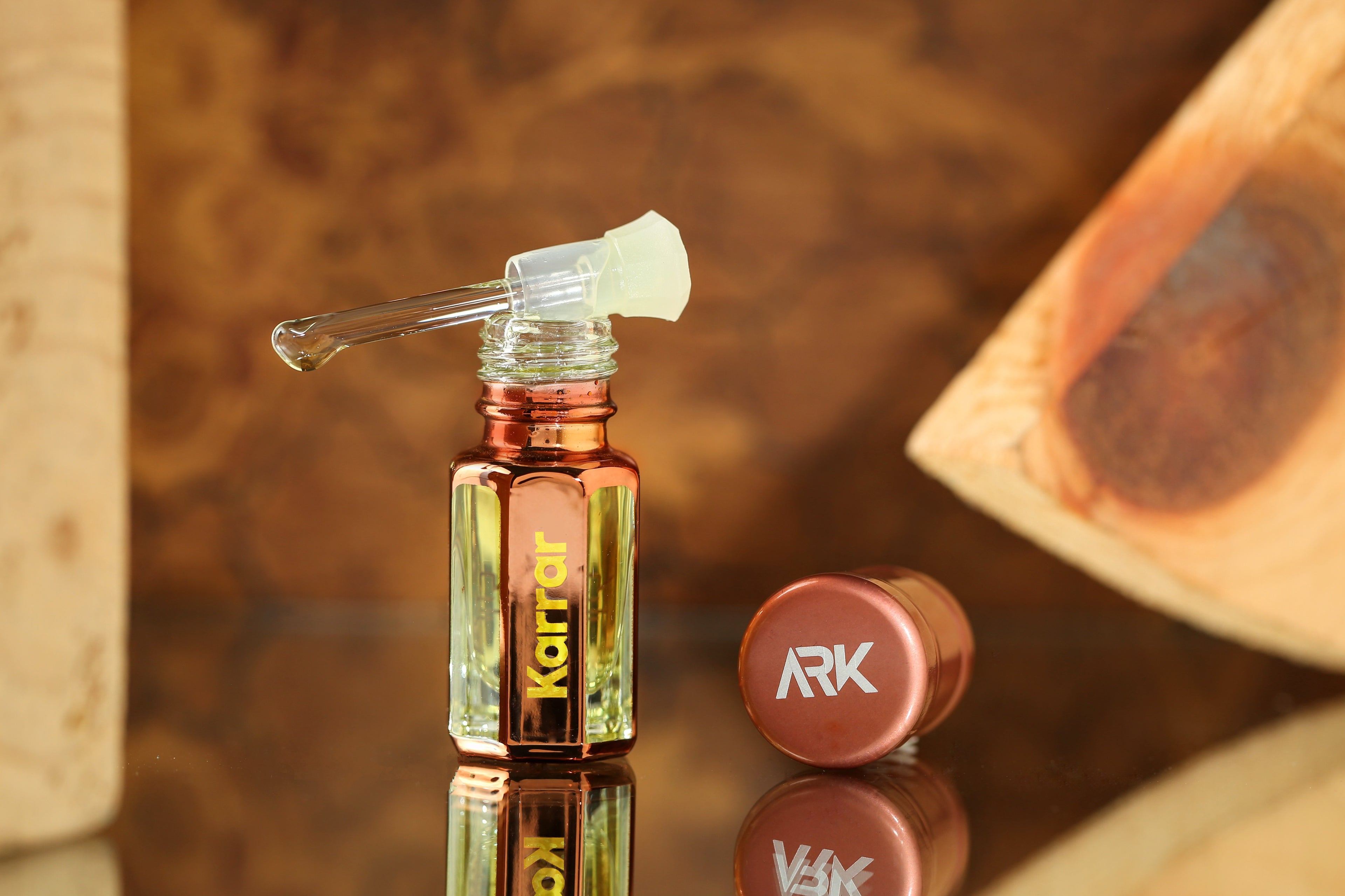 Karrar Attar by ARK Fragrances 3ml premium concentrated perfume oil with glass stick applicator displayed on wood background best warm woody scent online delivery in Lahore Karachi Islamabad Faisalabad and Pakistan