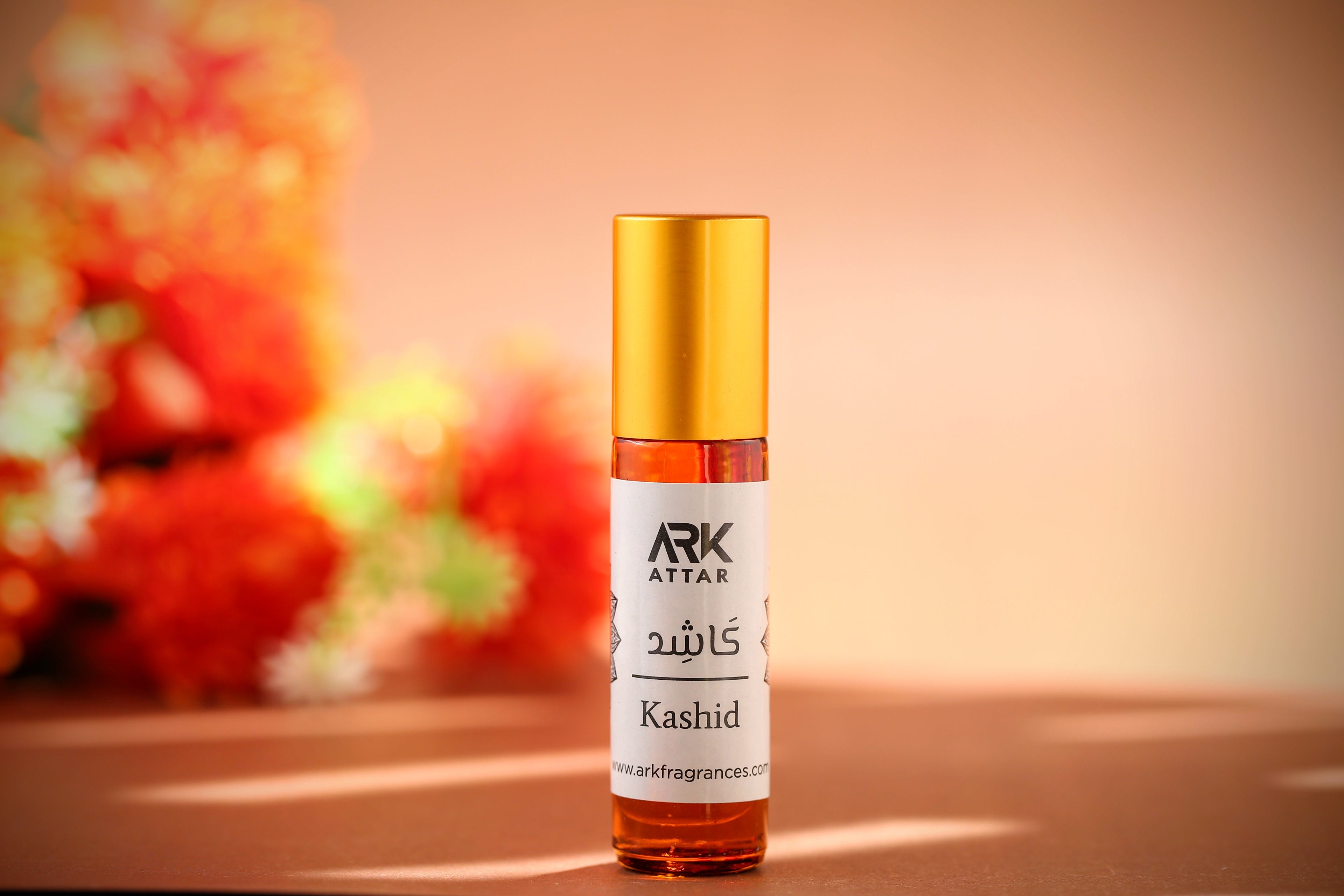 Kashid Attar by ARK Fragrances 6ml premium roll-on perfume oil displayed against a warm floral background. A rich and inviting fragrance featuring a sophisticated blend of Warm Spices, Earthy Woods, and Amber notes. This concentrated, alcohol-free scent is perfect for the Winter season and daily wear. We provide original attar delivery in Karachi, best selling perfume in Lahore, luxury fragrance in Islamabad, and fast shipping to Rawalpindi, Multan, Peshawar, Gujranwala, and nationwide across Pakistan.