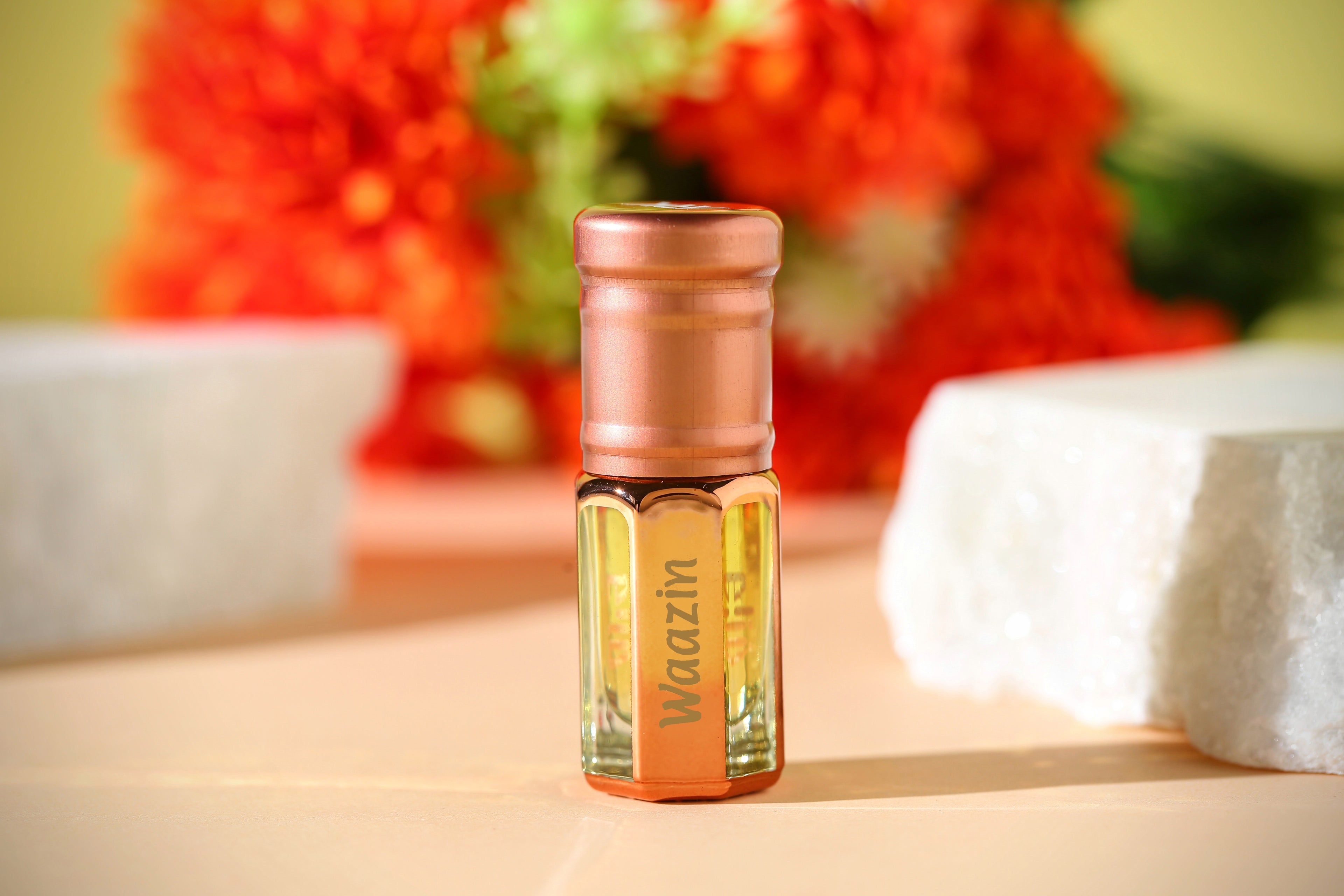 Waazin Attar by ARK Fragrances displayed with vibrant orange marigold flowers. Premium traditional floral perfume oil in gold bottle. Best long-lasting scent for festive occasions in Pakistan.