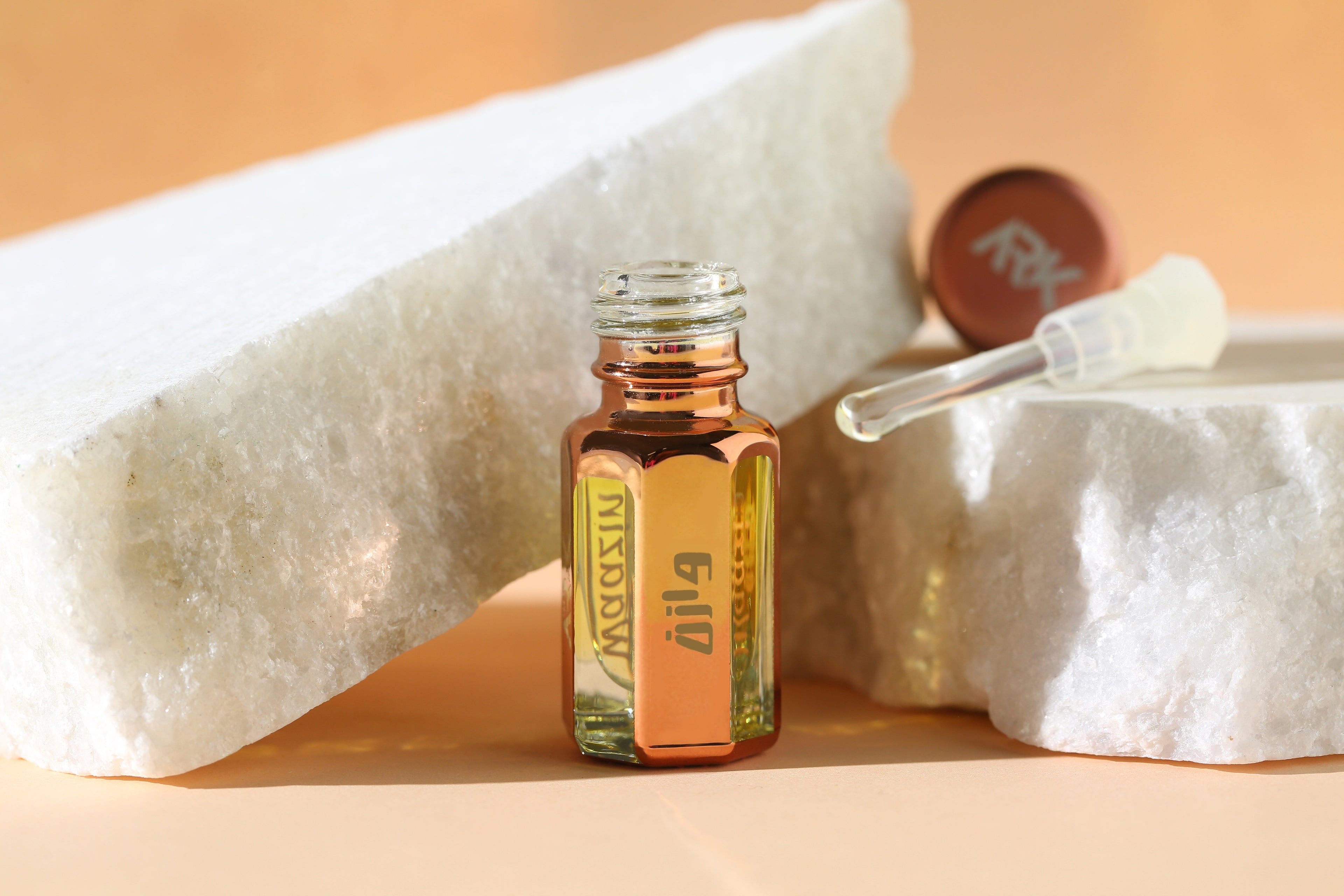 Waazin Attar bottle by ARK Fragrances displayed on a white stone. Premium alcohol-free long-lasting perfume oil with glass applicator. Best original scent in Pakistan.