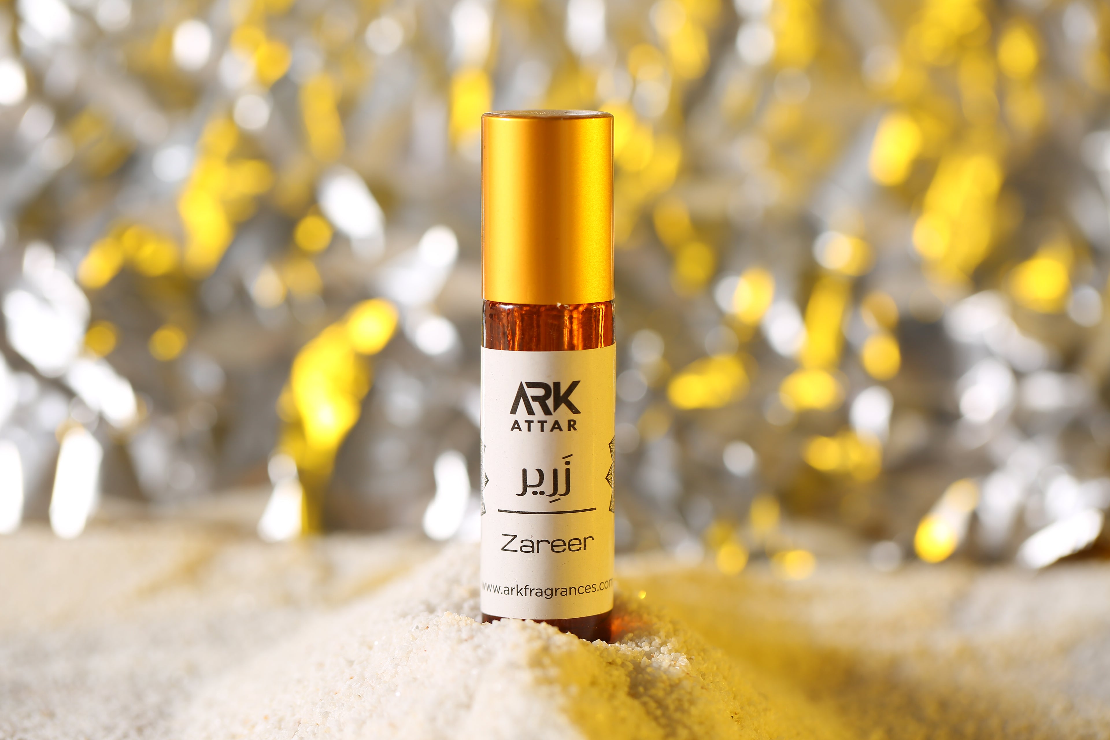 Zareer Attar by ARK Fragrances 6ml roll on perfume oil with gold cap displayed on white sand with festive background best gift online delivery in Lahore Karachi Islamabad Rawalpindi Multan Peshawar Gujranwala Hyderabad Sialkot Quetta and Pakistan