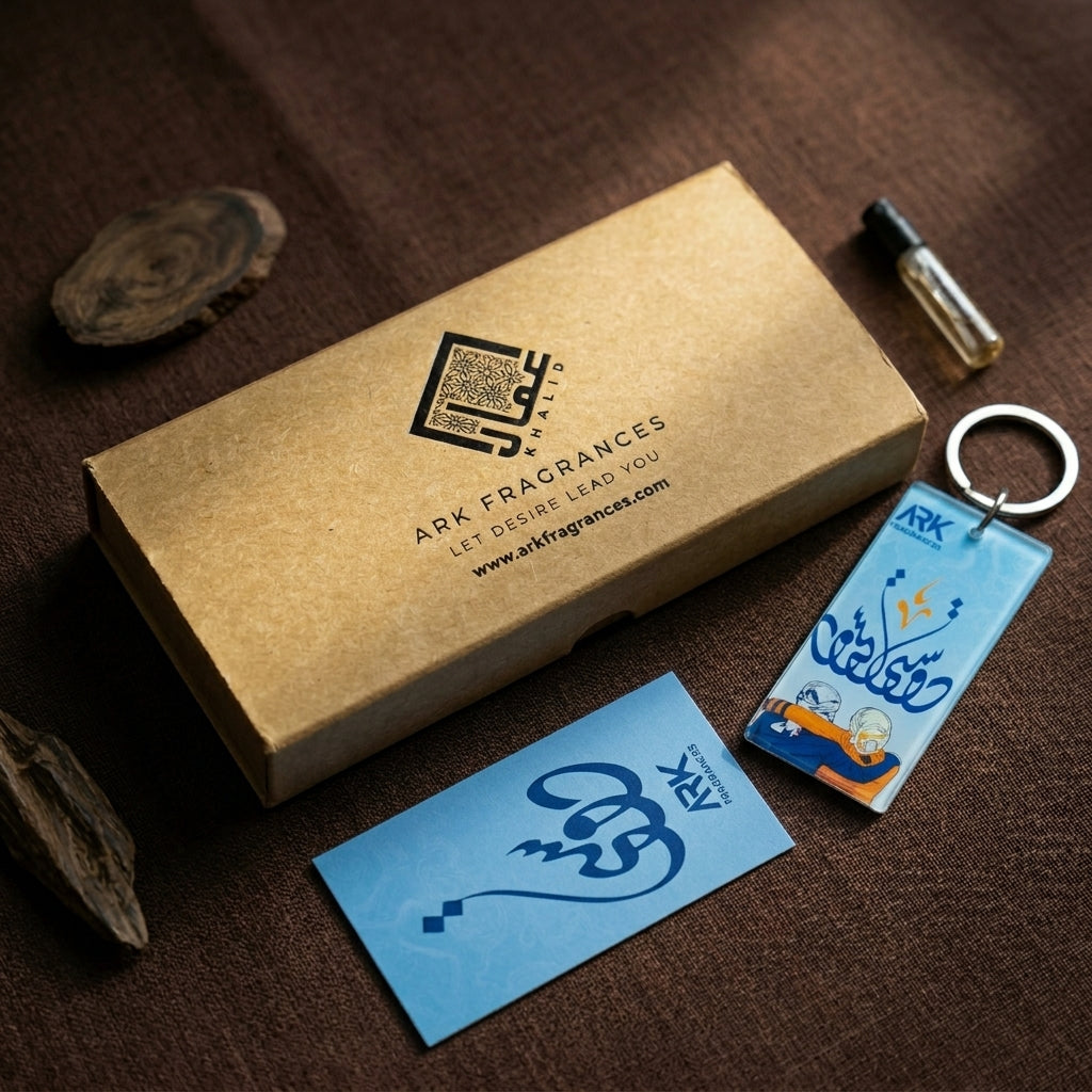 Premium light blue acrylic keychain featuring Islamic calligraphy and an illustration of two people embracing, placed next to an ARK Fragrances box.